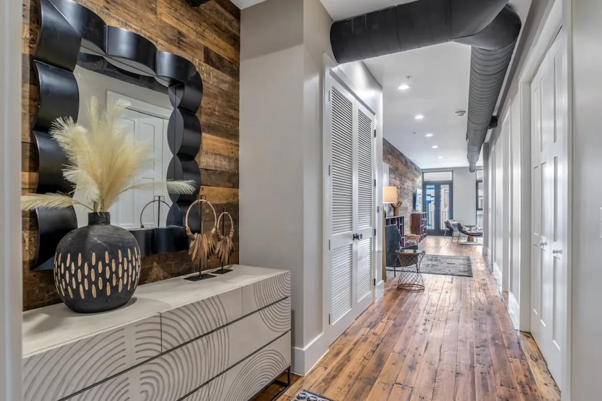 A thoughtfully designed entryway with a decorative mirror, a stylish sideboard, and a vase with dried flowers. The arrangement sets a warm, inviting tone and offers a glimpse into the home’s curated style.