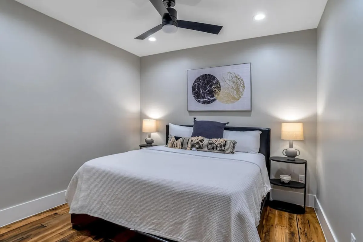 A cozy king-sized bed is the focal point, paired with coordinating bedside lamps and inviting artwork. The lighting is soft, and the space radiates comfort and warmth, making it an ideal setting for relaxation and rejuvenation.